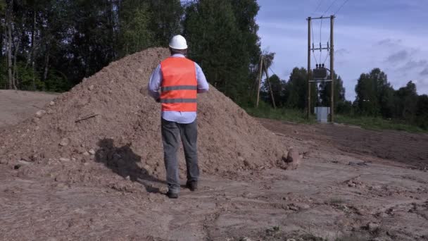 Engineer communicates near gravel pile — Stock Video