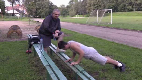 Jóvenes deportistas hacen flexiones y ejercicios en el estadio — Vídeos de Stock