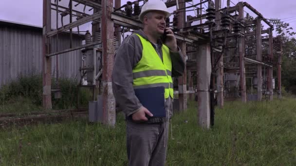 Elettricista con smartphone e documentazione a piedi in sottostazione — Video Stock