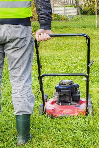 Trabalhador empurrando cortador de grama no jardim — Fotografia de Stock