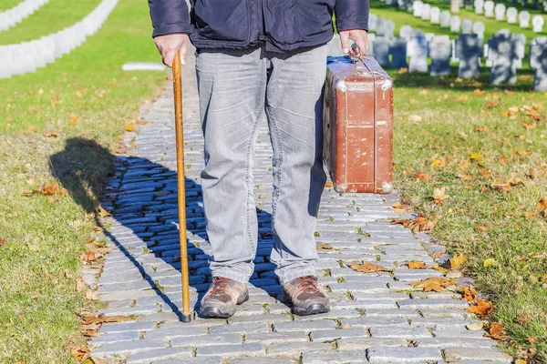 Hombre con bastón y maleta vieja en el cementerio — Foto de Stock
