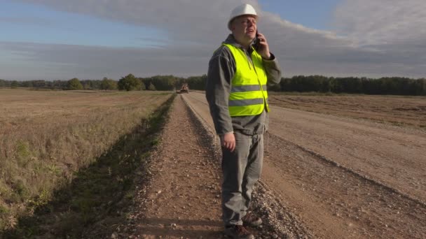 Инженер дорожного строительства разговаривает по телефону — стоковое видео
