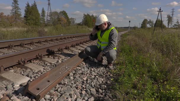 Trabajador del ferrocarril hablando por teléfono inteligente cerca de los carriles — Vídeos de Stock