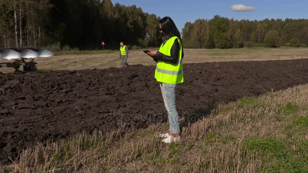 Фермер идет за трактором и проверяет поле — стоковое видео