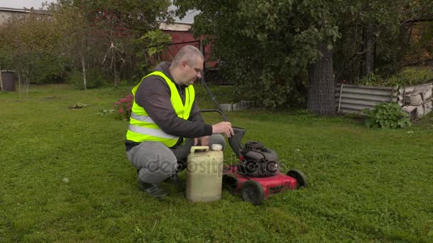 Man vullen opwaarts benzine op grasmaaier — Stockvideo