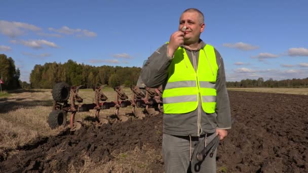 Farmář si heřmánkový květ vedle pluh na hřišti — Stock video