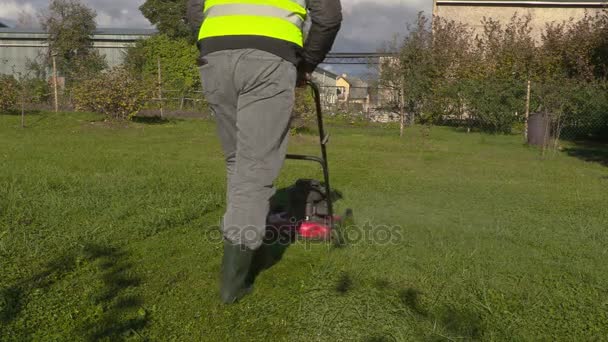 男は晴れた日に芝生芝刈り機の使用を開始します。 — ストック動画