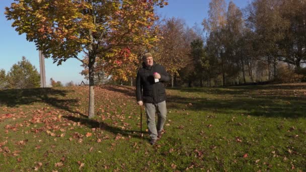 Hombre con caña beber café y caminar en el parque — Vídeo de stock