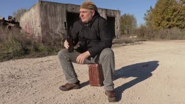 Sarhoş adam bavul üzerinde oturan boş şarap şişesi ile 