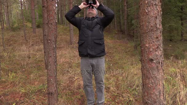 Mann starrt mit Fernglas in die Baumwipfel — Stockvideo