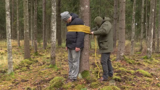 Gangster met touw in de buurt van de gijzeling in het bos in de buurt van boom — Stockvideo