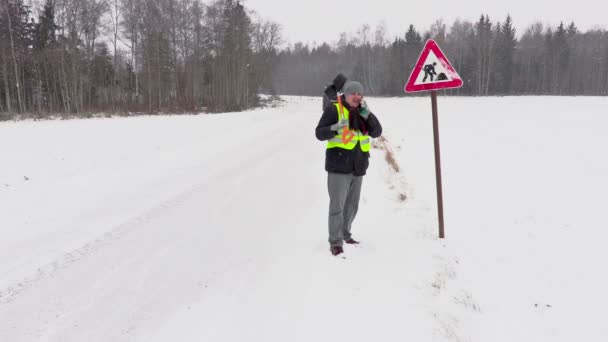 Працівник зі сніжною лопатою біля дорожнього знаку — стокове відео