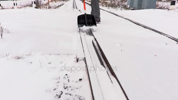Залізничний працівник чистий сніг від залізничного переходу — стокове відео