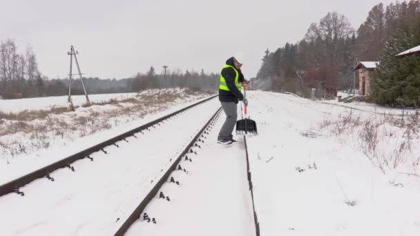 Empleado del ferrocarril limpia la nieve de la plataforma cerca del ferrocarril — Vídeos de Stock