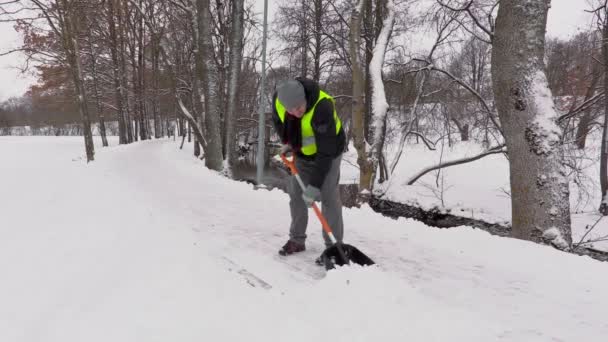 Vaktmästaren kasta snö från trottoaren — Stockvideo