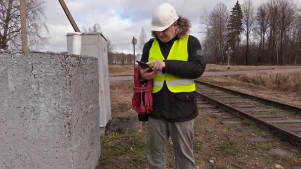 Электрик железной дороги использовать планшет возле железной дороги — стоковое видео