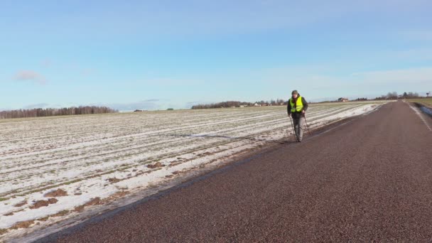 Randonneur avec bâtons de randonnée marchant sur la route en hiver — Video