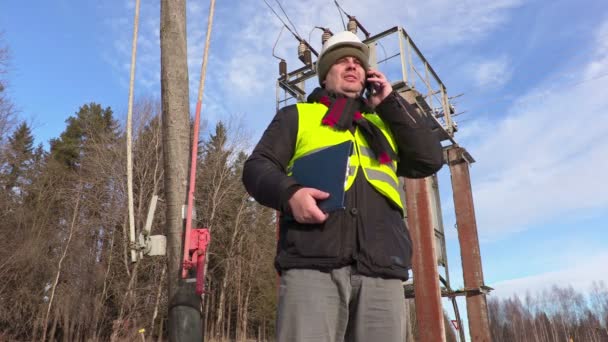 Elektriker ingenjör med smart telefon vid transformator — Stockvideo