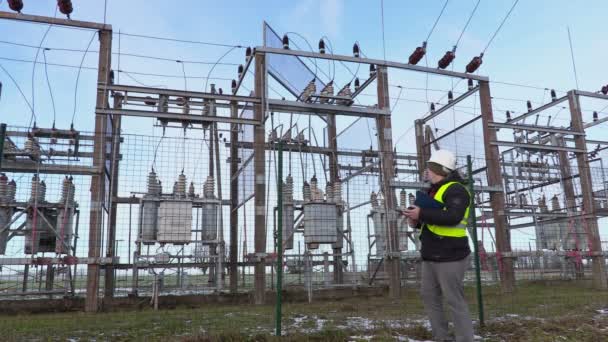 Electrician engineer writing and walking near substation in winter — Stock Video