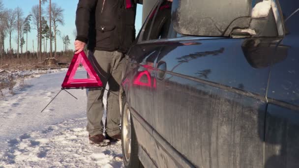 Mannen med varningstriangel som vandrar nära bilen i vinter — Stockvideo