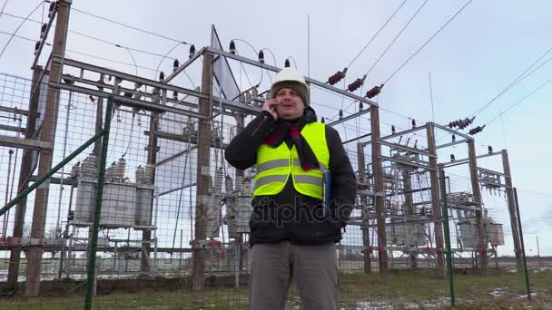 Elektriker ingenjör pratar smarta telefonen nära transformatorstation på vintern — Stockvideo