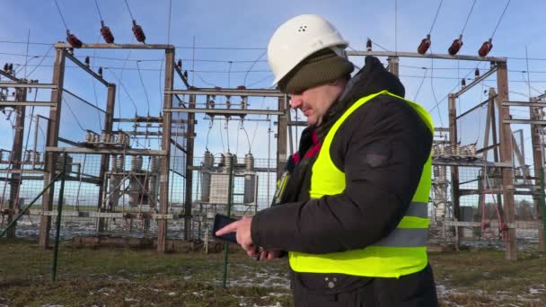 Inżynier elektryk, za pomocą tabletu w pobliżu podstacji w zimie — Wideo stockowe