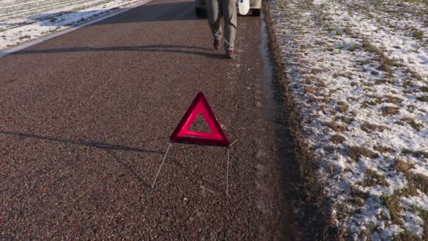 Homem com lata vazia perto de triângulo de aviso na estrada — Vídeo de Stock
