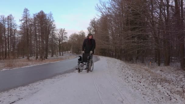 Hombre con silla de ruedas caminando cerca de la carretera — Vídeos de Stock