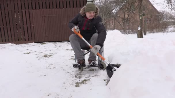 Behinderter im Rollstuhl mit Schneeschaufel im Hof — Stockvideo