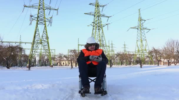 Disabled worker on wheelchair using tablet near to high-voltage lines — Stock Video