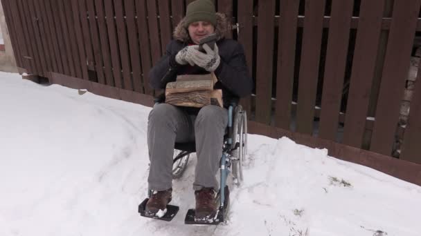 Людина з обмеженими можливостями на інвалідному візку з дерев'яними колодами, що розмовляють по телефону — стокове відео