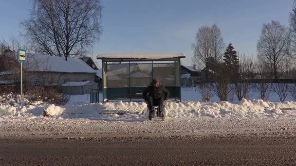Ανάπηρο άνθρωπο σε αναπηρικό αμαξίδιο, περιμένοντας το λεωφορείο στο χειμώνα — Αρχείο Βίντεο