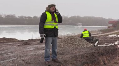 Cep telefonu ve kaldırım tuğla sıralama arkasında çalışan konuşurken inşaat mühendisi 