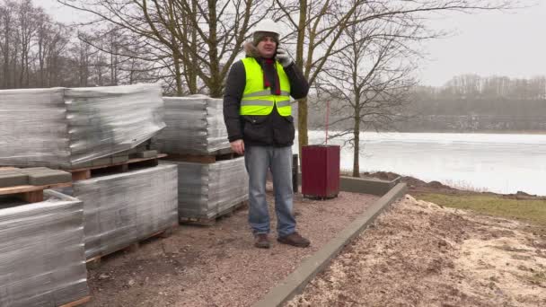 Ingenieur bouwkunde praten over slimme telefoon in de buurt van bestrating bakstenen — Stockvideo