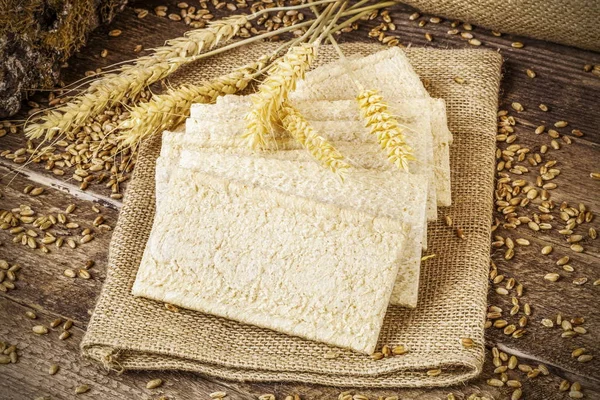 Pane croccante con grani e orecchie sul tavolo di legno — Foto Stock