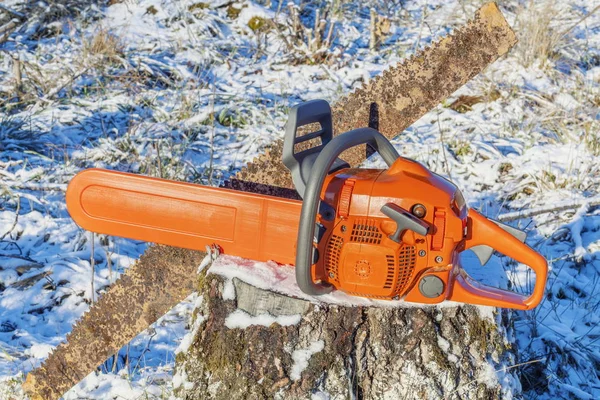 Chainsaw with old hand saw on stump in forest — Stock Photo, Image
