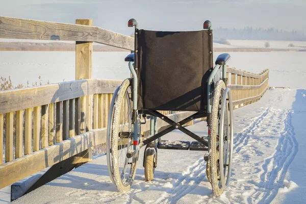 Fauteuil roulant sur le pont près du lac en hiver — Photo