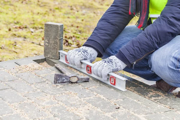 Bouwvakker met waterpas in de buurt van onvoltooide bestrating — Stockfoto