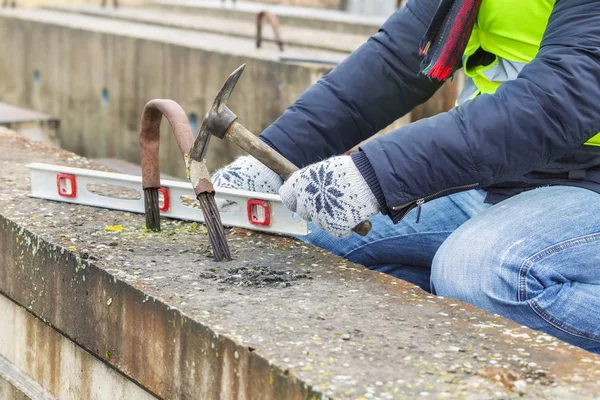 Stavební dělník, práce s kladivem poblíž betonových bloků — Stock fotografie