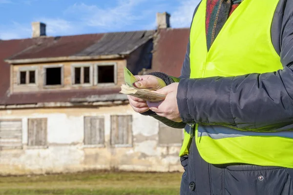 Travailleur muni de billets en euros près d'une maison abandonnée — Photo