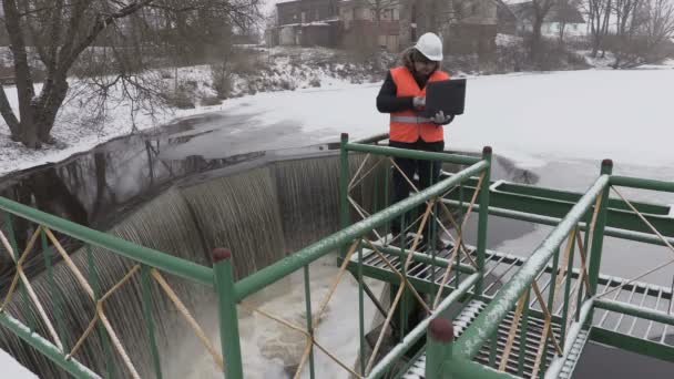 Ingenieur werken met de laptop in de buurt van floodgate in de winter — Stockvideo