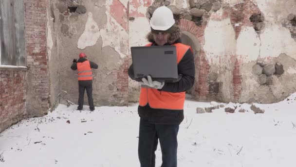 Construction engineer using laptop and talking with worker — Stock Video