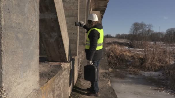 Ingenieros toman fotos en la tableta cerca del puente — Vídeos de Stock