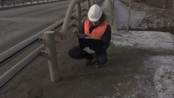 Engenheiro usando laptop perto da ponte e indo embora — Vídeo de Stock