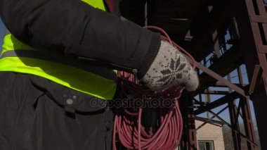 İşçi metal tankları yakınındaki güç kablosu ile