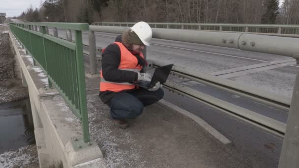Ingenieur met behulp van de laptop op de brug — Stockvideo