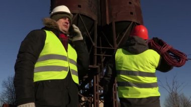 İşçiler ile akıllı telefon ve güç kablosunu yakınındaki metal tankları