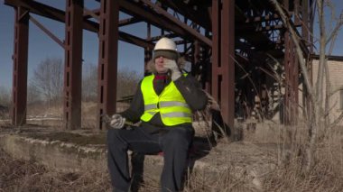 Oturma ve metal tankları yakınındaki telefonda konuşurken alt