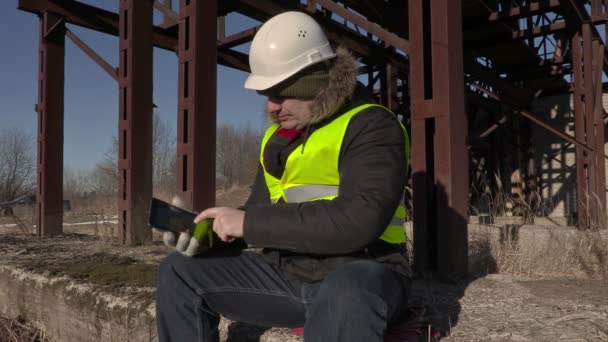 Trabajador sentado y usando tableta cerca de tanques de metal — Vídeo de stock