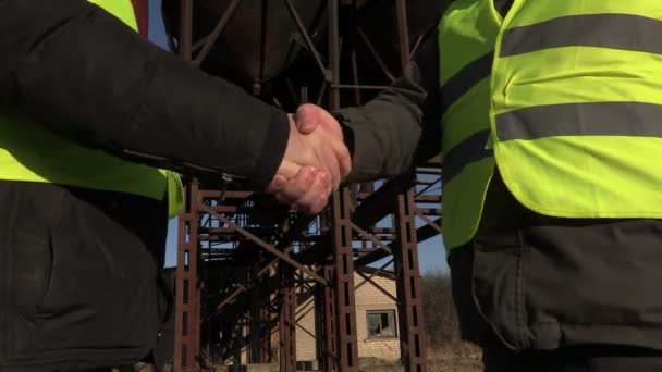 Ingenieros estrechando manos cerca de tanques — Vídeos de Stock